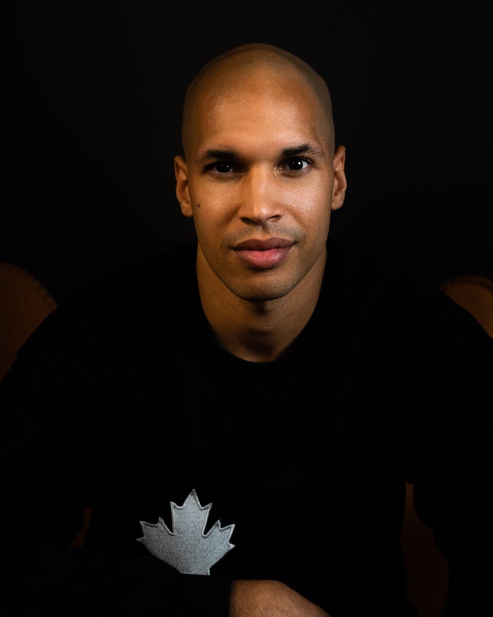 Portrait of a Black man, wearing a black long sleeve shirt, with a white Maple leaf on the top left hand corner of the shirt. His name is Marc Lafleur, CEO and co-founder of truLOCAL