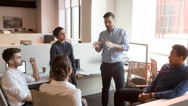 Serious team leader talk to diverse business people at meeting