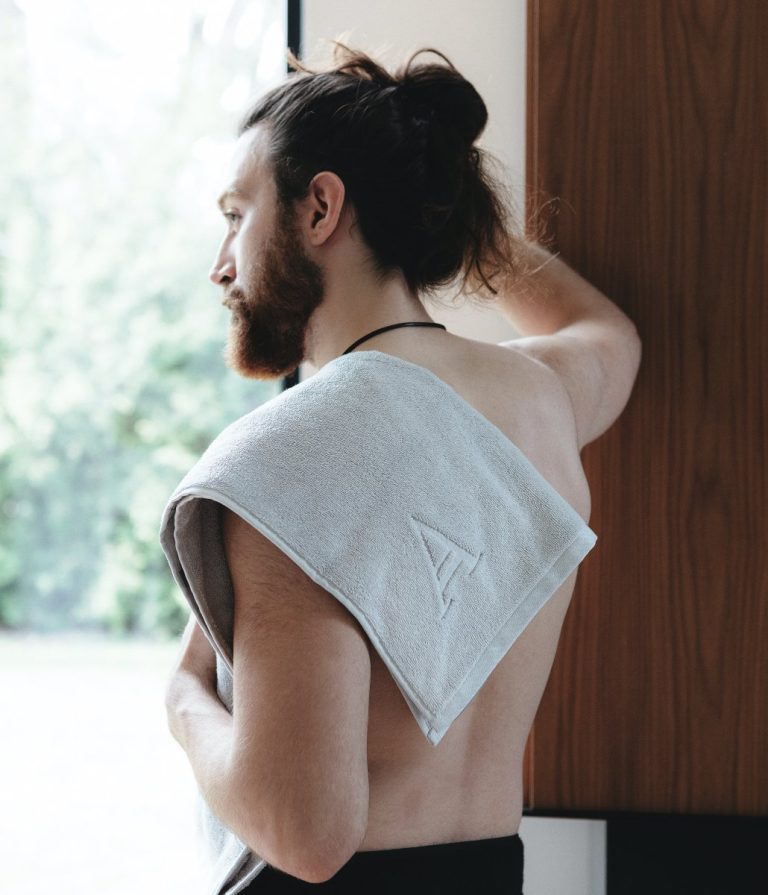 A man looks off in a distant with an Aestate towel draped over his shoulder to represent the new towel brand byAashish Nathwani