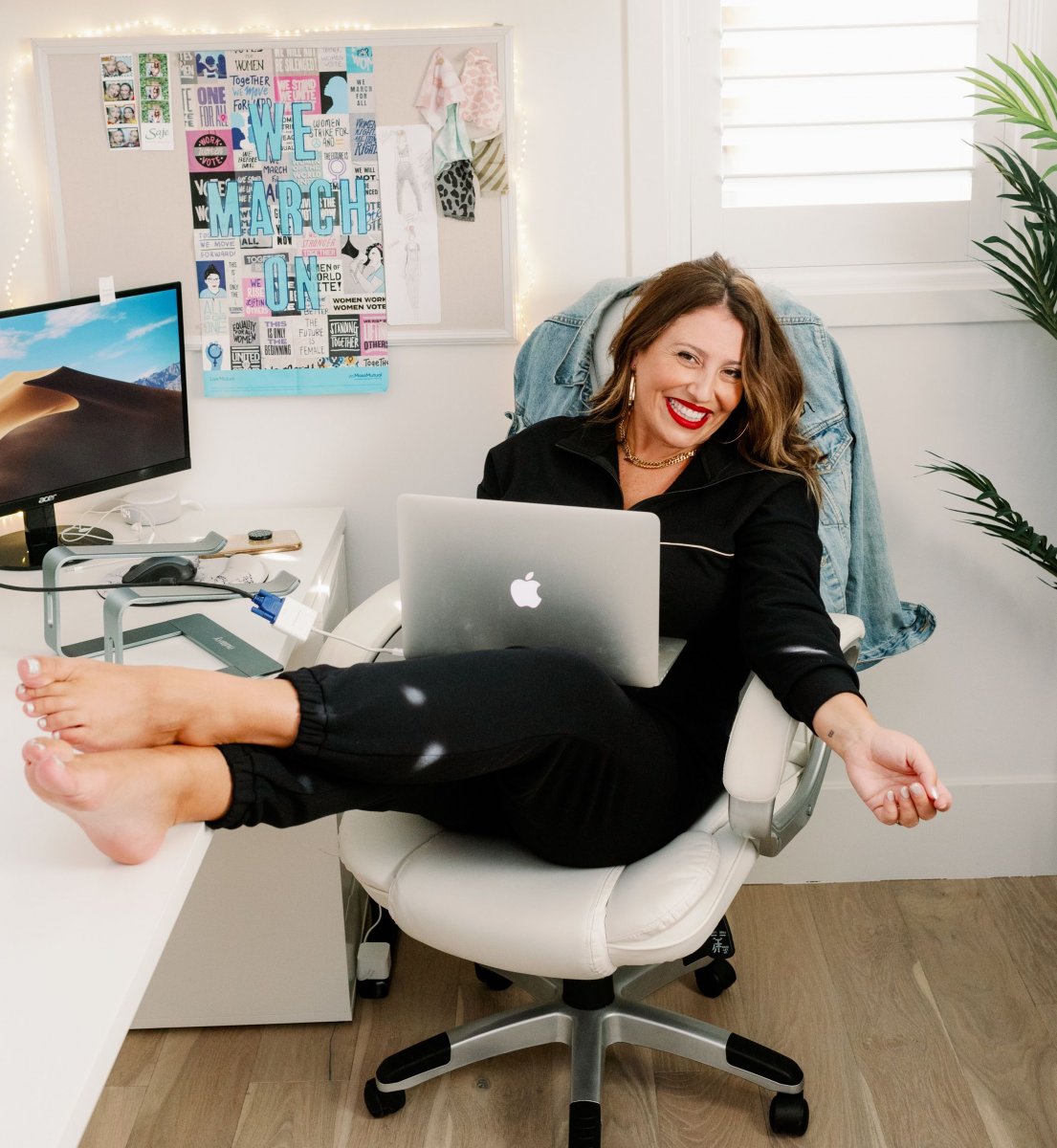 Ashley Freeborn of Smash + Tess, sits in an office chair at with her feet up on her desk, and smiles at the camera.