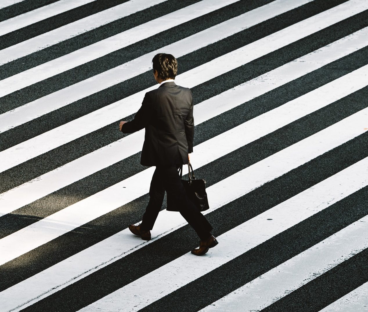 business man walking across a sidewalk