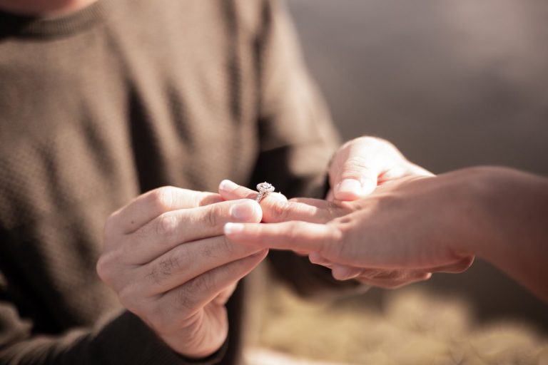 Someone putting an engagement ring on a hand which is the exact opposite of a non-traditional proposal.