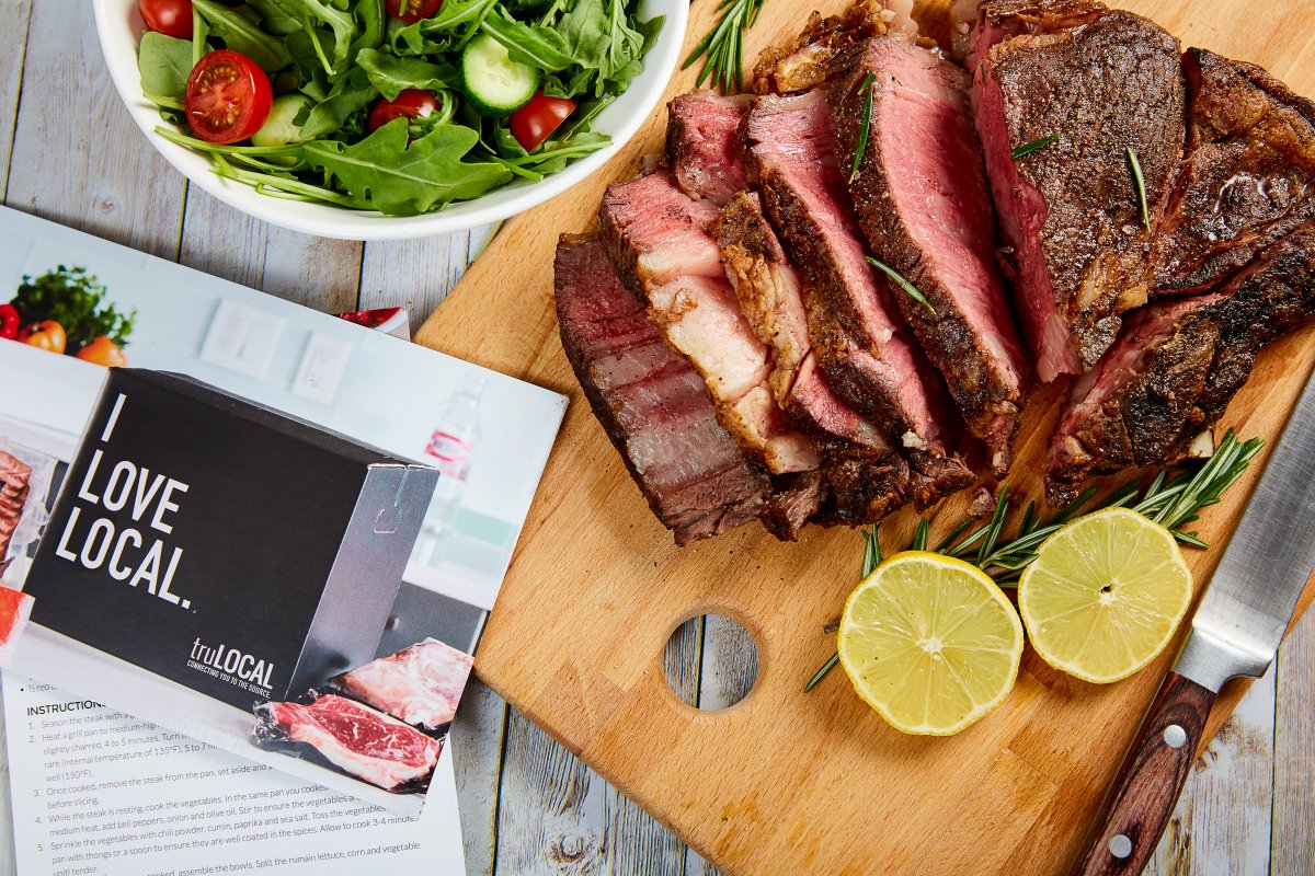 Picture of a cooked roast on a cutting board with lemon, a truLOCAL pamphlet sits on the counter beside it.