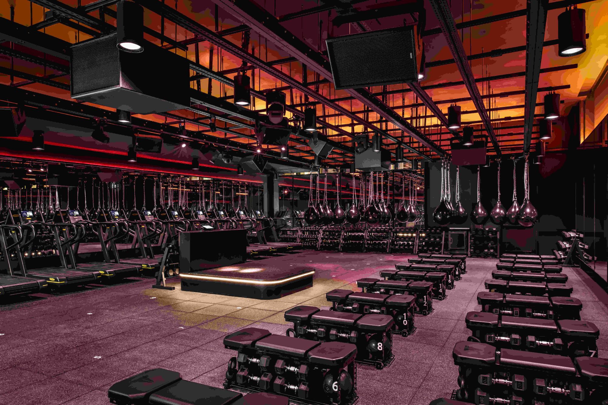 A red-lit workout room with various exercise gear.