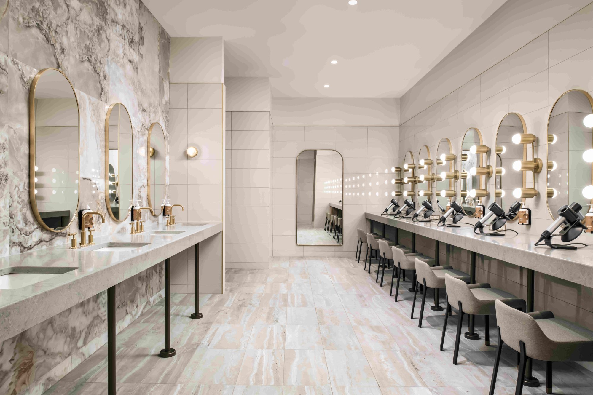 Spa-like change room with mirrors and marble floors with hair dryers.