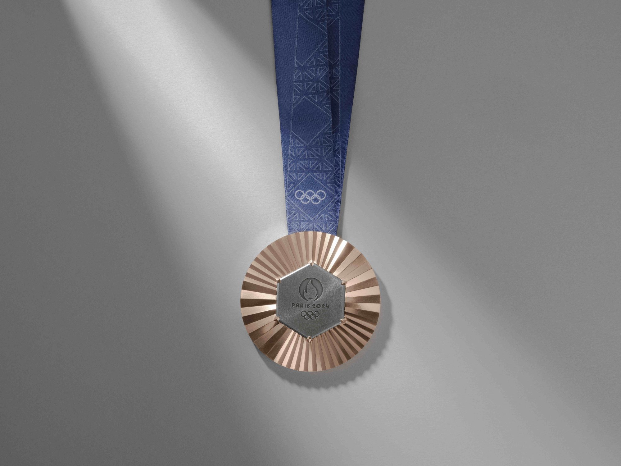 Olympic Bronze medal with Eiffel tower metal hanging on a blue satin ribbon.