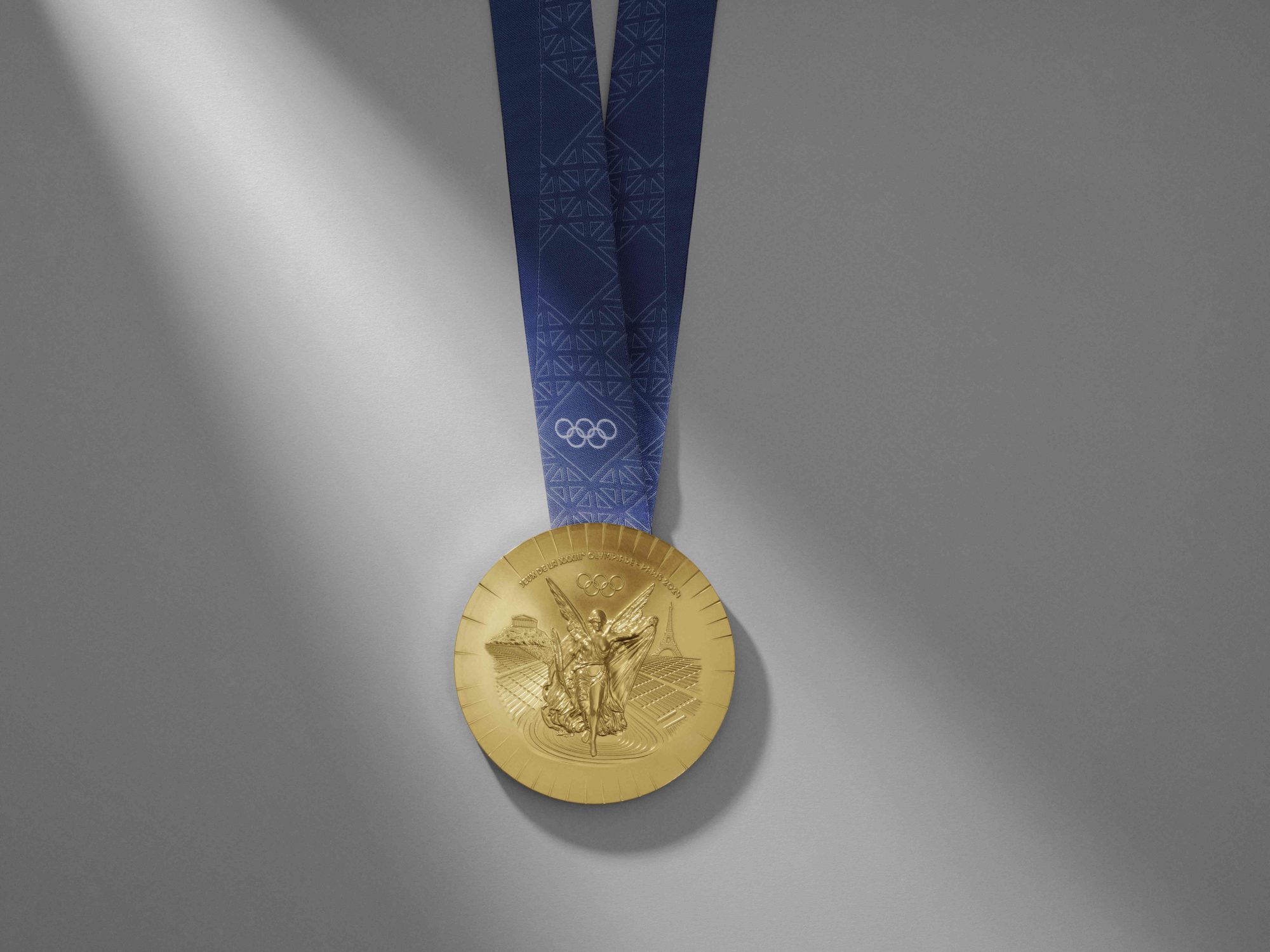 Chaumet Olympic Gold Medal hanging on a blue satin ribbon.