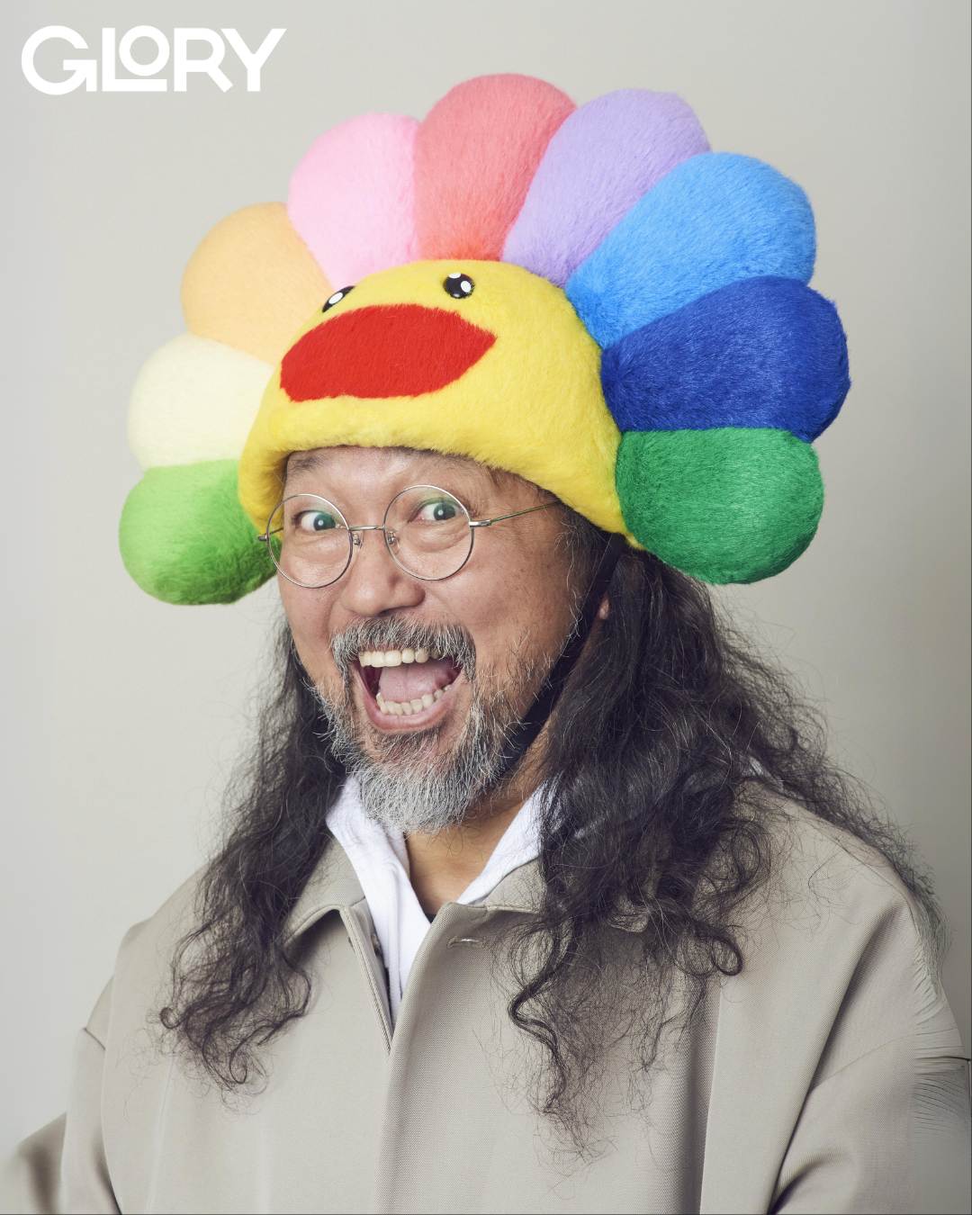 Takashi Murakami wearing a rainbow hat and smiling into the camera.