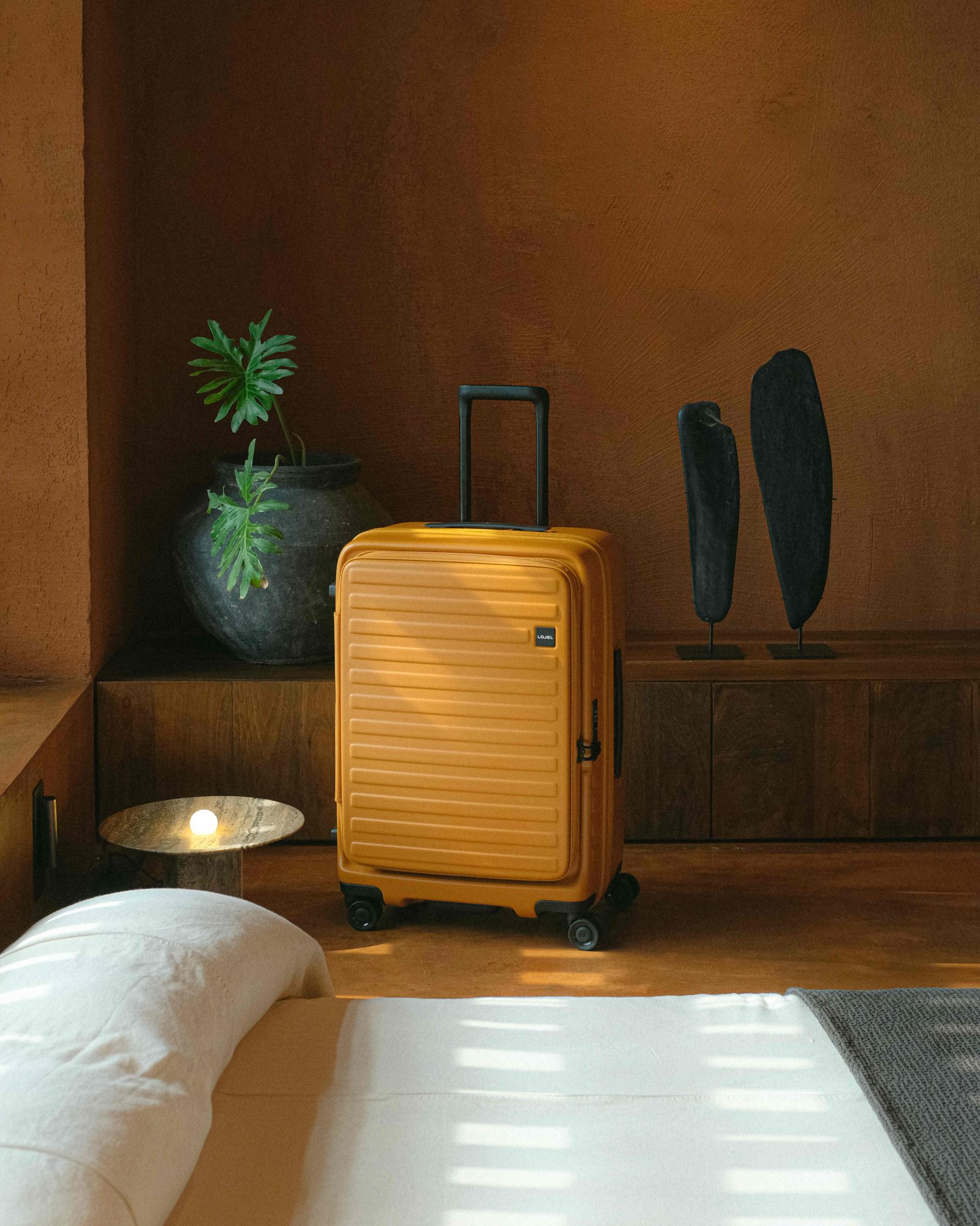 Yellow carry-on suitcase in an earthy sun-lit hotel room.